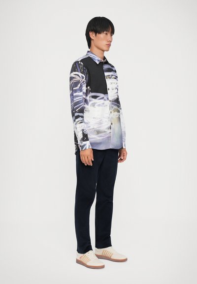 Overhemd met knopen en een gesplitst ontwerp met zwarte en abstracte grafische prints, lange mouwen en een kraag. Gekozen in combinatie met donkere broeken en sneakers.