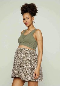 Top de alças em tom verde oliva com textura canelada, combinado com uma saia fluida beige que possui um padrão de manchas de leopardo em cor castanha, textura suave e cintura elástica.