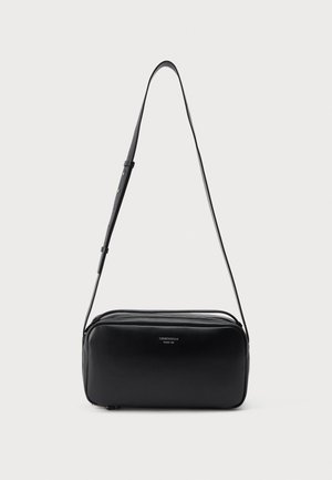 Sac bandoulière rectangulaire en cuir noir avec sangle réglable et fermeture éclair argentée sur le dessus, sur un fond blanc uni.