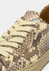 Ανοιχτό μπεζ αθλητικά παπούτσια από δέρμα με υφή φιδιού, με κρεμ κορδόνια και φυσική πλεγμένη σόλα από τζούτ.