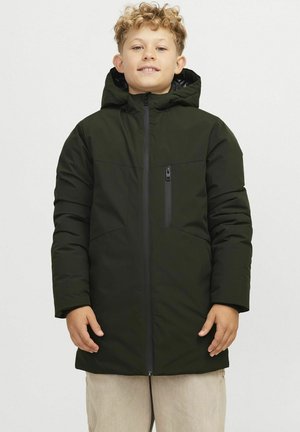 Chaqueta acolchada verde oscuro con capucha, que presenta una cremallera frontal, dos bolsillos laterales y una textura suave. Lleva puesta sobre pantalones beige claros.