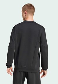 Black sweatshirt with a round neckline, drop shoulders, and ribbed cuffs. Features a smooth texture and "AEROREADY" label at the hem.