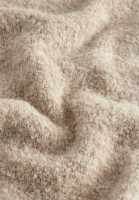 Tessuto a trama beige con una superficie morbida e texture, caratterizzato da filati soffici in un motivo sciolto e annodato. Adatto per coperte o rivestimenti.