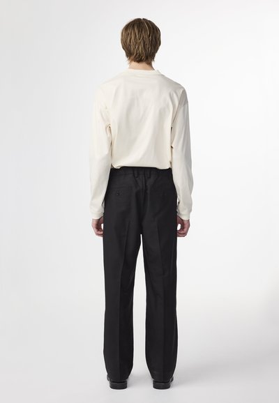 Lange mouwen crèmekleurig shirt met een ontspannen pasvorm, gecombineerd met zwarte wijde broek met achterzakken en een vlakke voorkant.