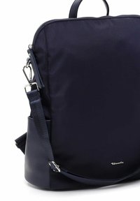 Mochila azul marino con cremalleras y clip plateados, correa ajustable, asa superior redondeada y pequeño logo metálico de la marca cerca de la base.
