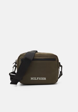 Oliwkowa torebka na ramię, wykonana z trwałego materiału, z przednią kieszenią na zamek błyskawiczny, regulowanym paskiem i białym logo "HILFIGER".