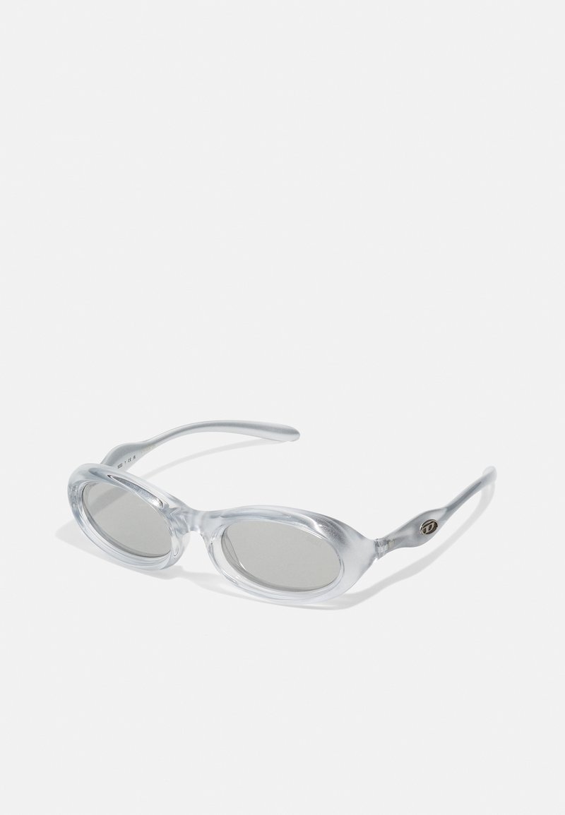 Óculos de sol ovais claros com lentes ligeiramente coloridas, hastes finas e acabamento brilhante. Apresenta um pequeno logotipo na lateral.