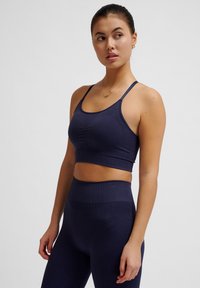 Marine-blauwe crop top met dunne bandjes, gestructureerde stof en geplooide details in het midden. Gecombineerd met hoge taille bijpassende leggings.