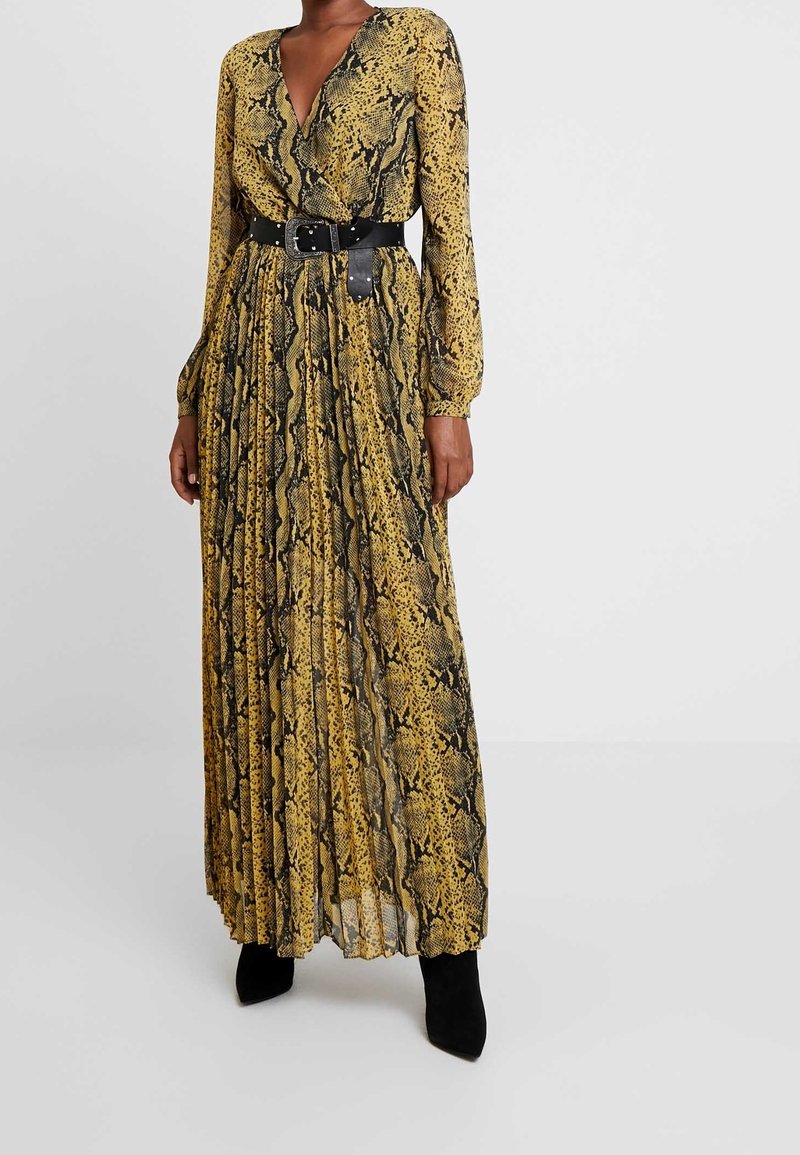 Robe longue plissée jaune et noire avec un motif serpent, dotée d'un décolleté en V profond et de manches longues, cintrée à la taille par une ceinture noire.
