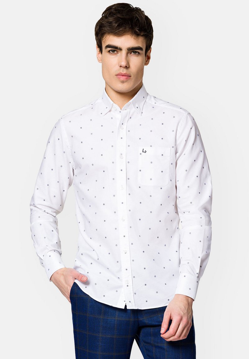 Biała koszula z guzikami z małymi niebieskimi kropeczkami, elastyczny materiał bawełniany i kieszeń na lewej piersi. Posiada wyłogi z ostrymi końcami oraz listwę z guzikami.