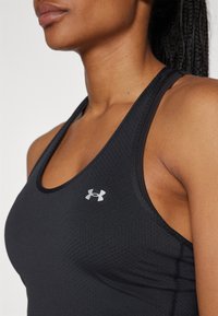 Černý sportovní tílko s texturovaným vzorem, designem na závodní záda a malým stříbrným logem Under Armour v oblasti levé hrudi.