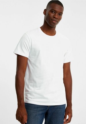 White cotton t-shirt with a crew neck, short sleeves, and a fitted design. Worn with dark blue jeans, showcasing a smooth texture.