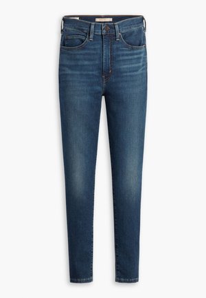 Jean skinny bleu foncé en denim, avec des poches avant, une taille avec passants de ceinture et une texture légèrement décolorée. Idéals pour un style décontracté.