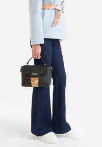 Zwarte handtas met een textuurrijke afwerking en gouden accenten; beschikt over een voorvak met een kaartontwerp en een handvat aan de bovenkant om te dragen.