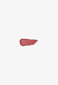 Coup de pinceau grossier d'un échantillon de rouge à lèvres mat rose poudré sur fond blanc uni.