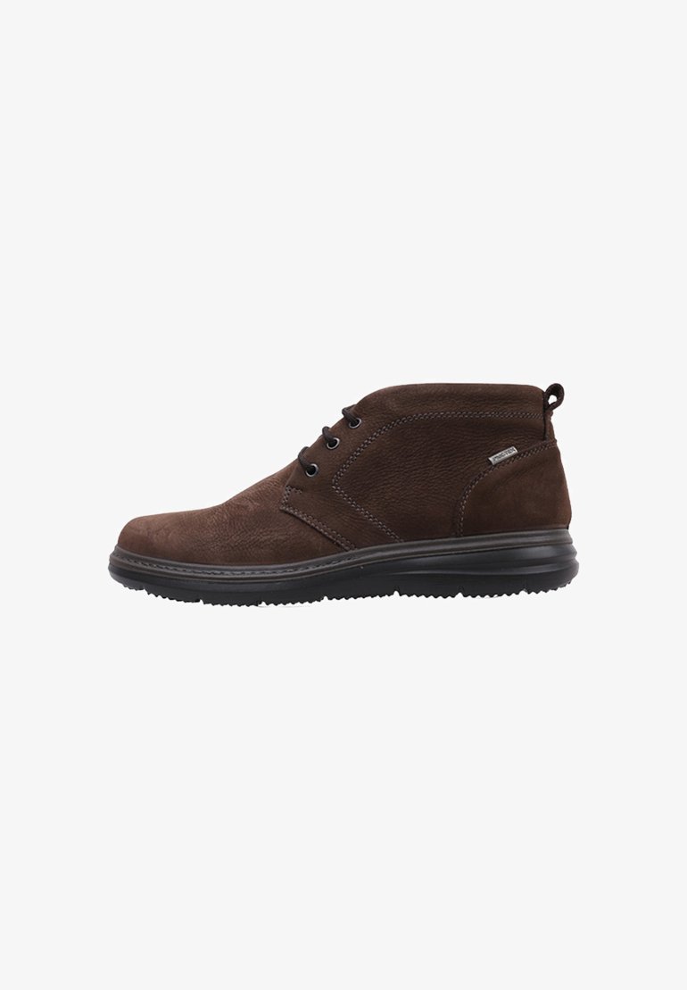 Botas de tobillo de ante marrón con puntera redondeada, detalles laterales y suela de goma negra. Presenta dos ojales para los cordones y una lengüeta en la parte trasera.