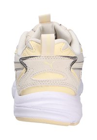 Puma sneakers feature a light yellow and cream upper with textured accents, a padded collar, and a white rubber sole for comfort.
