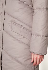 Gray padded jacket with diagonal stitching, a side pocket, and elastic cuffs. Smooth texture and lightweight design.