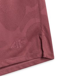 Gros plan sur un tissu bordeaux texturé avec des motifs cousus et le logo brodé "4F" près du bord de l'ourlet d'un vêtement.