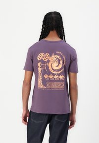 Short-sleeve purple cotton t-shirt featuring a large orange graphic design on the back, depicting abstract shapes and a figure playing an instrument.