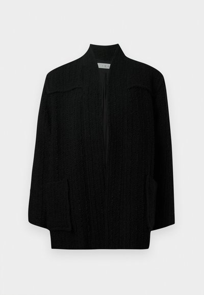 Černý pletený cardigan s texturovaným vzorem, otevřeným předním dílem a dvěma bočními kapsami. Má šálový límec a volný, oversized střih.
