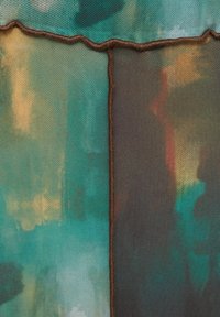 Gros plan sur un tissu texturé avec des panneaux cousus bleu-vert et brun foncé, présentant une couture irrégulière et ondulée ainsi que des motifs colorés abstraits.