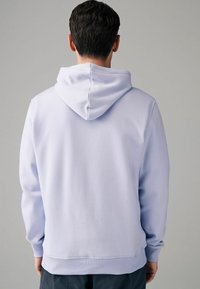 Helle lila Kapuzenpullover mit geripptem Saum und Bündchen, ausgestattet mit einer Kordelzugkapuze. Der Stoff wirkt weich und glatt, ohne sichtbare Muster oder Akzente.