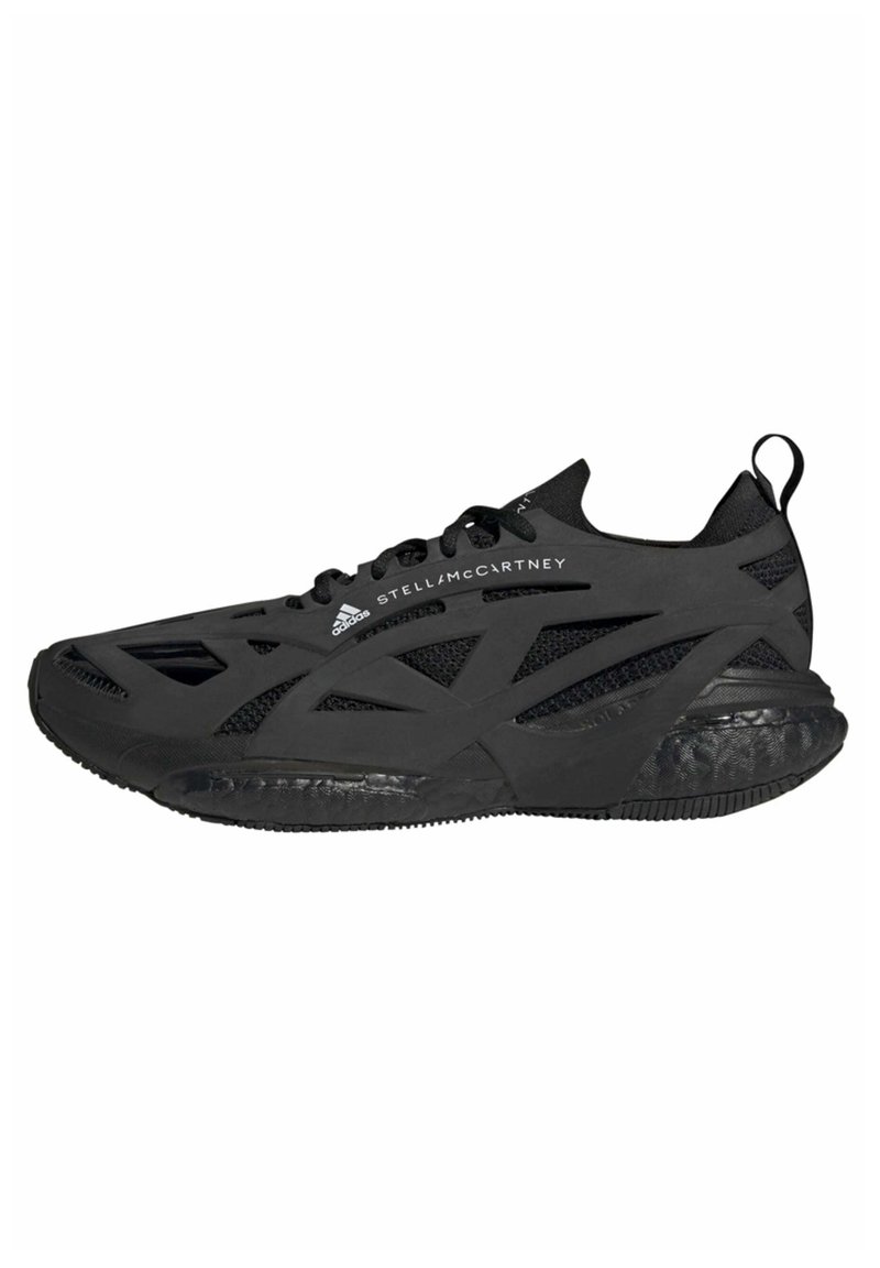 Chaussure de sport noire avec une tige en mesh léger, découpes géométriques, semelle en caoutchouc texturée et une languette à l'arrière pour un enfilage facile.
