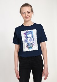 T-shirt blu navy con una grafica di un orso colorato con effetti acquerello, accenti di testo e schizzi di viola e blu.