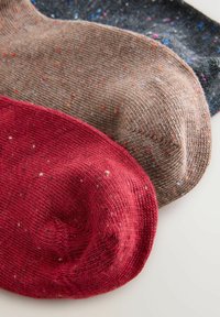 Drei Paar Socken: rot, braun und dunkelgrau. Strukturierter Strick mit bunten Sprenkeln. Rund geschnittene Zehenpartie.