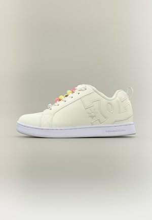 Baskets basses blanches avec œillets colorés pour les lacets et logo embossé sur le côté, présentées sur un fond neutre.
