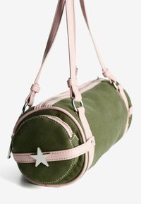 Borsa cilindrica verde con tracolle e bordature rosa, decorazione a stella argentata e chiusura con zip su sfondo bianco.