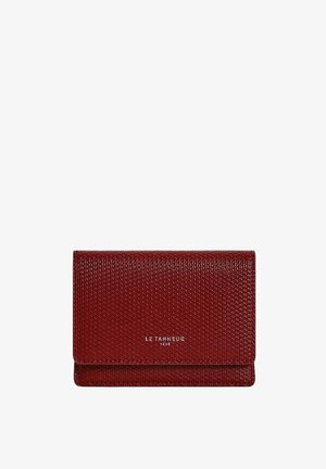 Cartera roja con textura y acabado suave, que presenta un diseño de solapa y un nombre de marca en relieve. Forma compacta y rectangular.