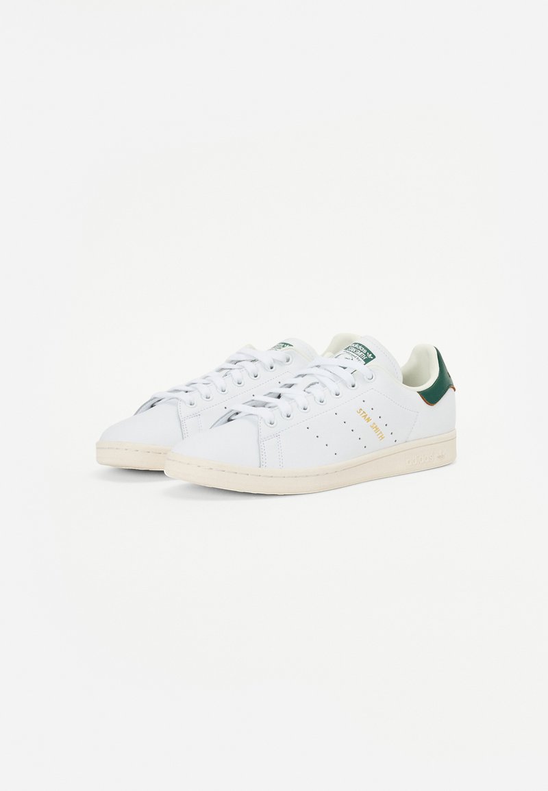 Baskets en cuir blanc avec des accents verts, bout rond, laçage sur le devant, détails perforés sur les côtés et semelle en caoutchouc crème.