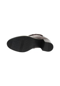 Chaussure en cuir brun avec une semelle en caoutchouc noir texturé, dotée d'un talon carré et de détails tressés sur le dessus.