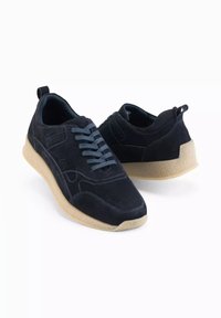 Baskets en daim bleu marine avec lacets bleu clair, bout arrondi et semelle en caoutchouc beige texturé. Comprend une sangle à l'arrière et des accents sur les côtés.