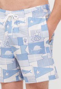 Lys blå svømmeshorts med et mønster av fisk, nautiske flagg og ikoner. Laget av teksturert stoff med elastisk midjebånd og snøring.