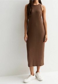 Robe midi marron côtelée sans manches à coupe droite, associée à des baskets blanches. Le tissu est texturé et légèrement ajusté.