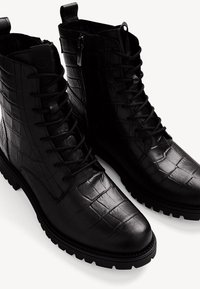 Schwarze Leder-Stiefeletten mit Krokodilstruktur, ausgestattet mit Schnürung, einem seitlichen Reißverschluss und robusten Gummisohlen.