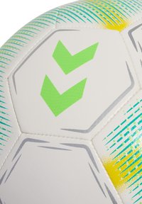 Pallone da calcio bianco con motivi a contrasto verdi e gialli, caratterizzato da due loghi verde a chevron, pannelli esagonali e superficie testurizzata.