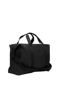 Sac de voyage noir en tissu durable, doté de deux poignées supérieures, d'une bandoulière réglable et d'un compartiment principal zippé.