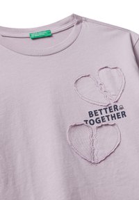 Svetlefialové bavlněné tričko s dvěma vyšitými srdíčky a otevřeným švem, s textem "LEPŠÍ SPOLEČNE" v černé barvě.