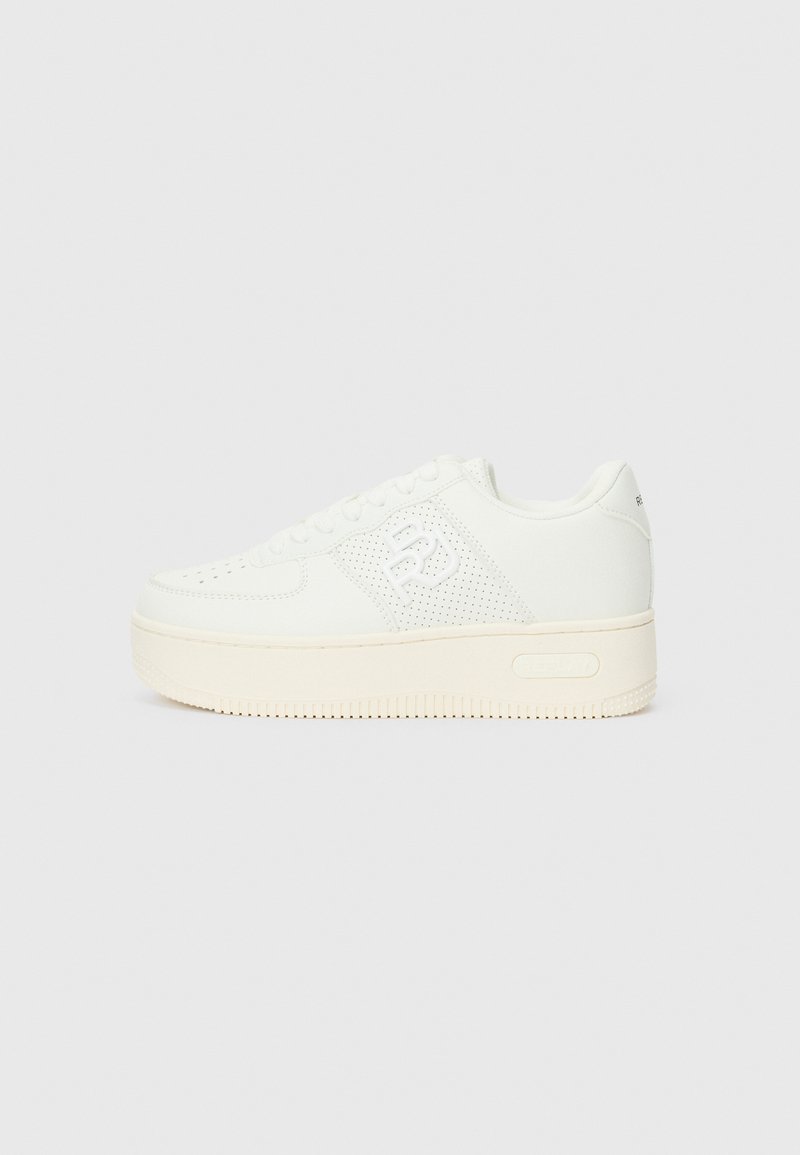 Fehér sneaker, texturált bőr felsőrésszel, perforált díszítésekkel, gumitalppal és logóval az oldalon. Lapos fűzők és lekerekített orrforma.