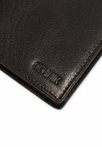 Ciemnobrązowy skórzany portfel o teksturowanej powierzchni i przeszywanych krawędziach, z wytłoczonym na rogu napisem "OCHNIK".