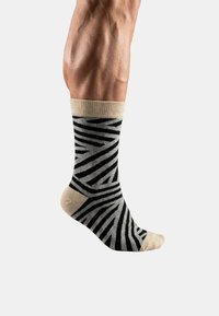 Calcetines a rayas negras y beige hechos de un material suave, con puño elástico, punta reforzada y un diseño estampado.