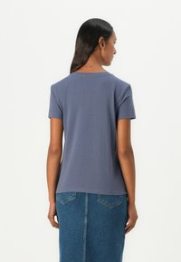Grå t-skjorte med korte ermer og avslappet passform, laget av myk stoff, kombinert med et denimskjørt som har baklommer og rett design.