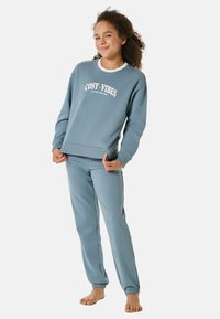 Blaues Baumwollsweatshirt mit dem Aufdruck "COSTY VIBES", kombiniert mit passenden blauen Jogginghosen. Beide haben gerippte Bündchen und einen lässigen Schnitt.
