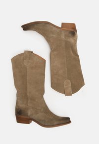 Stivali cowboy in suede marrone chiaro con punta appuntita, tacco impilato e linguette per il sollevamento. Presentano una cucitura decorativa e una texture liscia.