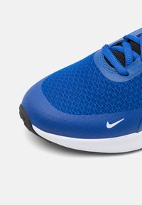Baskets de sport bleues avec un matériau en maille, des accents noirs et une semelle blanche. Elles sont dotées de lacets et d'un petit logo Nike blanc sur le côté.