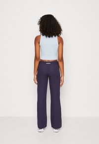 Un débardeur court bleu clair associé à un pantalon large noir marine. Le pantalon est doté d'une taille élastique et de poches.